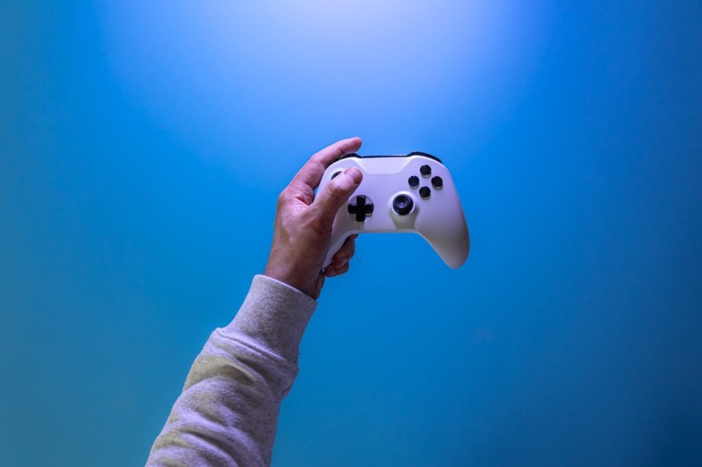 Male hands hold a gamepad on a blue background, copy space.