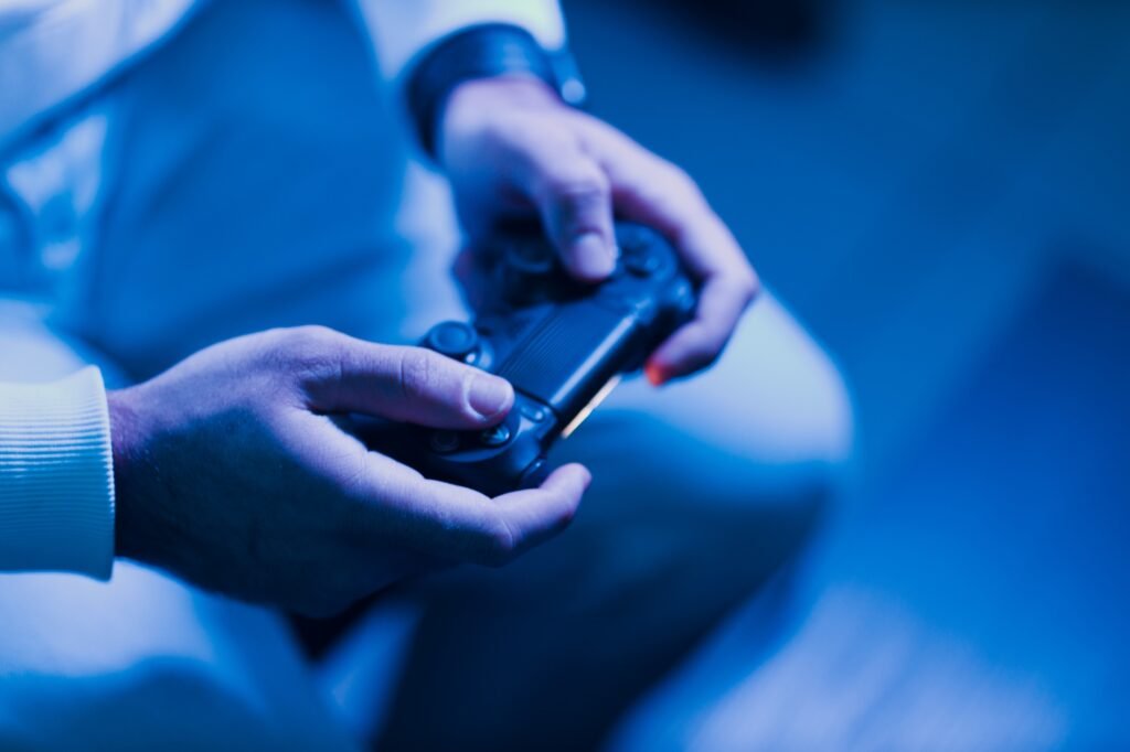 Young guy plays on game console with gamepad sitting on chair